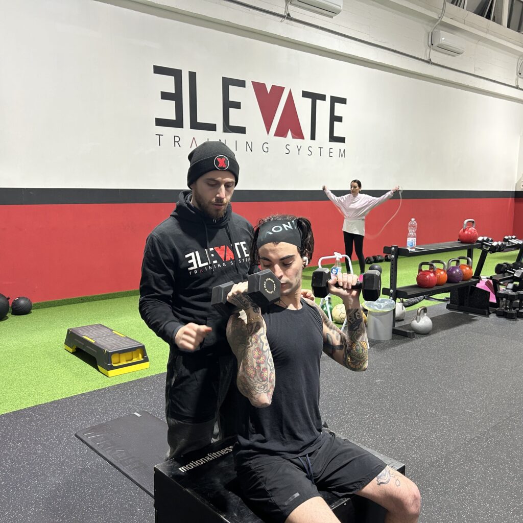 Coach che segue un cliente durante un esercizio con i manubri