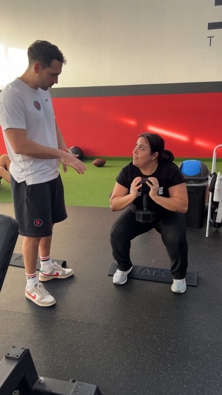 Coach che segue una cliente nello squat con il kettlebell