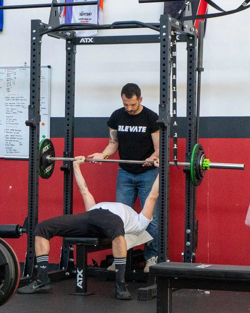 Personal trainer che assiste un cliente alla panca piana